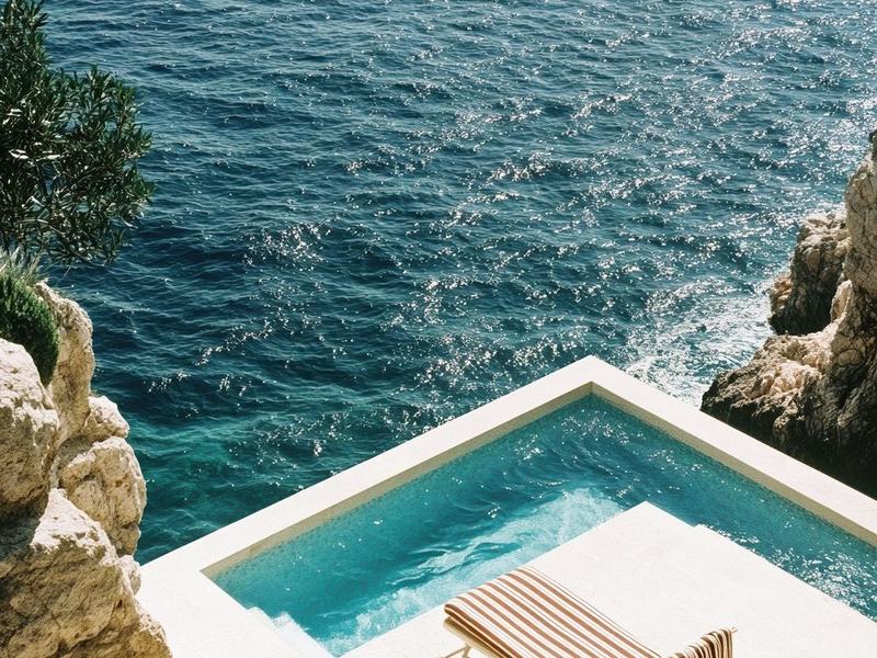 A cliffside plunge pool and lounger above the sea